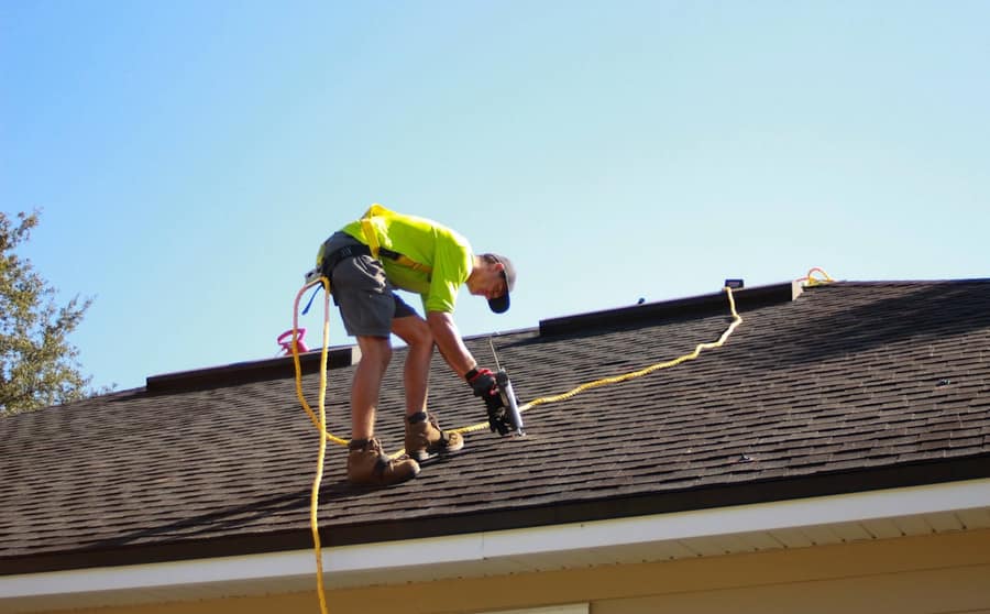 A roofer on a residential roof inspecting the surface